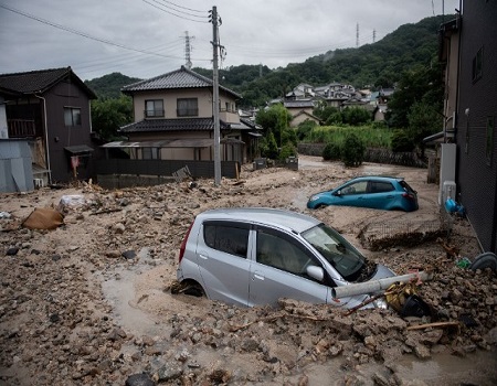 A picture shows cars trapped in the mud after floods in Saka, Hiroshima prefecture on July 8, 2018. - Japan's Prime Minister Shinzo Abe warned on July 8 of a "race against time" to rescue flood victims as authorities issued new alerts over record rains that have killed at least 48 people. (Photo by Martin BUREAU / AFP)