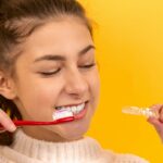 Lady brushing her teeth and holding braces
