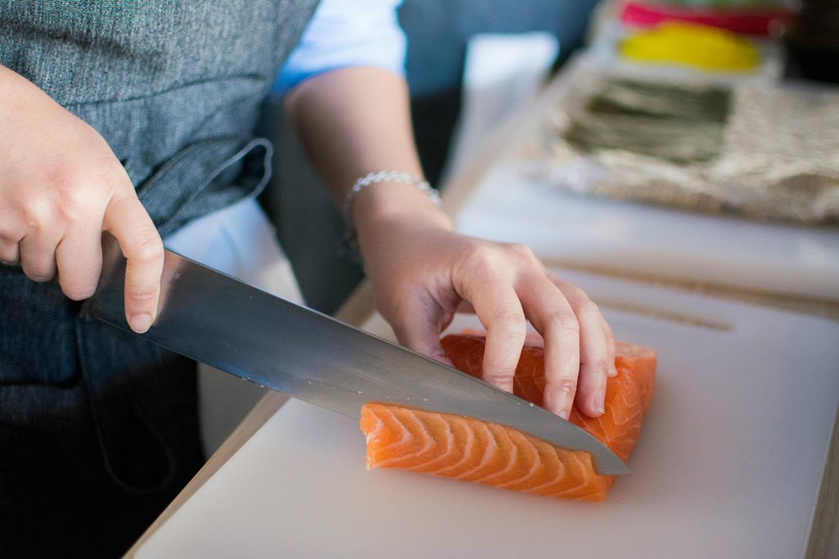 Hands cutting salmon with a knife