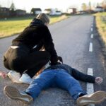 lady adminstering CPR to a man on the road