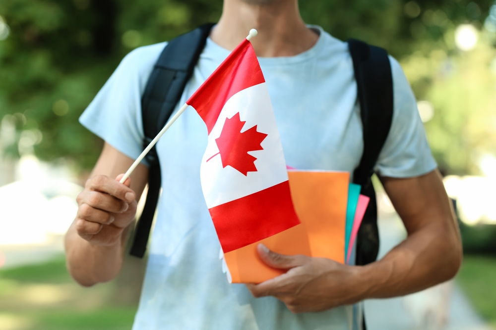 Canada Student Visa: A picture showing a foreign student in Canada with backpack holding Canadian flag.
