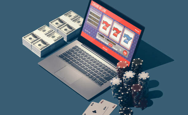Online casino games, slots and gambling: laptop with slot machine app, piles of chips and packs of dollars, winning and leisure concept