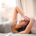 A woman lying down in pains from headaches. Trying to find ways to relieve the headache naturally