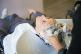 Someone adding shampoo to another person's hair