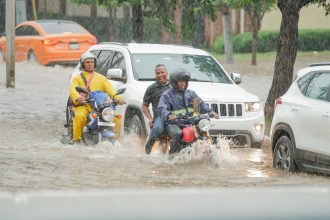 a group of people riding motorcycles through a flooded street