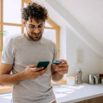 A man holding a phone and debit card