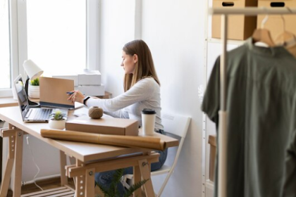 A woman sitting at the desk with a laptop and small boxes