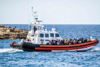 A rescue boat carrying a large number of people across the sea