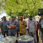 Custom officials standing beside impounded petroleum products