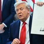 president Donald Trump holding the signed executive order for flag burners