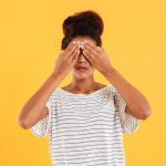 Young woman covering her eyes isolated