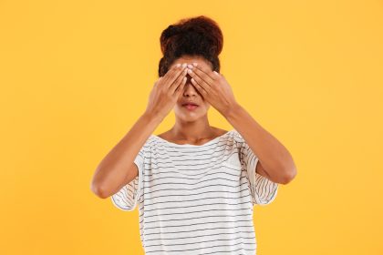 Young woman covering her eyes isolated